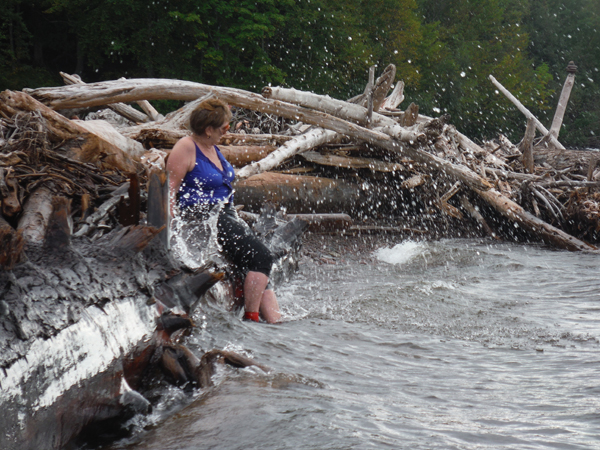 The waves are splashing against the logs and Karen.